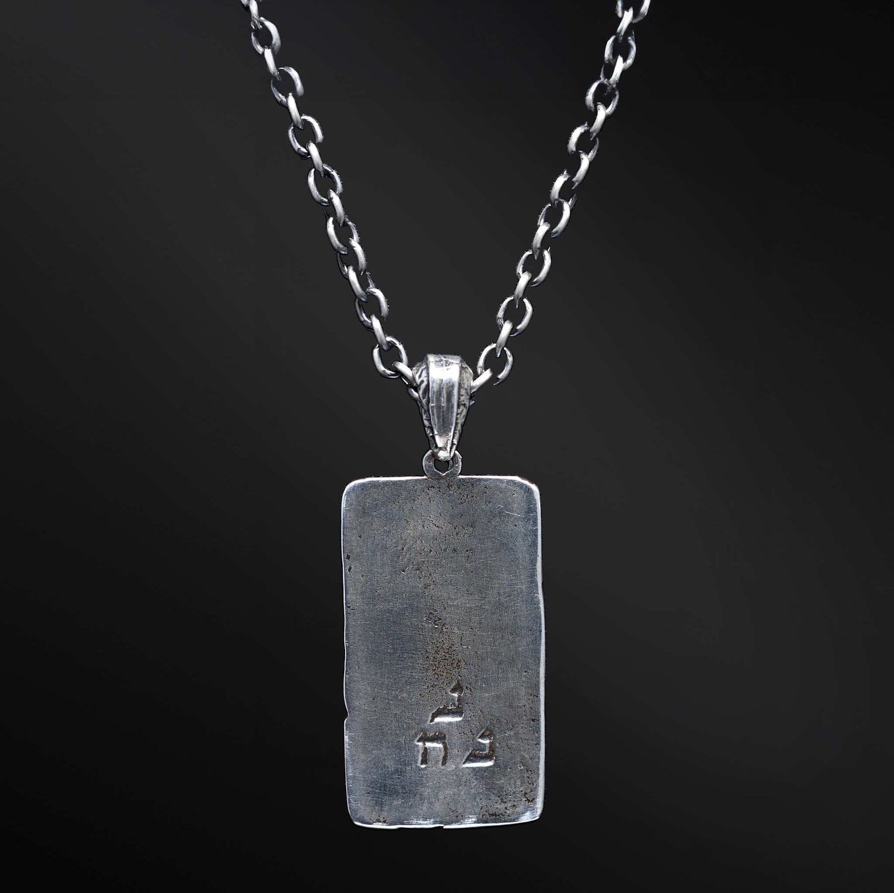 "Elkana Pendant: Unleash the power of your inner flame with the captivating Elkana pendant. Its elegant design showcases the phrase 'Aesh Sheli' engraved on a sleek plaque, representing the fire that resides within. Let its presence serve as a constant reminder of your inner strength, passion, and resilience as you navigate life's journey."