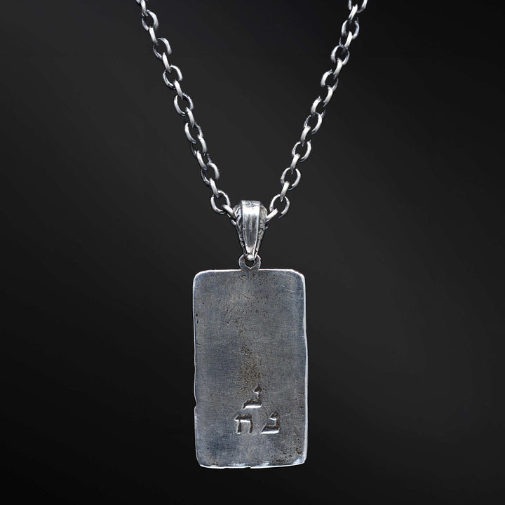 "Elkana Pendant: Unleash the power of your inner flame with the captivating Elkana pendant. Its elegant design showcases the phrase 'Aesh Sheli' engraved on a sleek plaque, representing the fire that resides within. Let its presence serve as a constant reminder of your inner strength, passion, and resilience as you navigate life's journey."