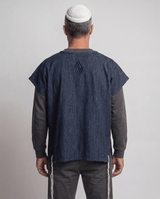 Man wearing tallit katan in denim, back view showing the Aesh Sheli flame embroidery, Kameart
