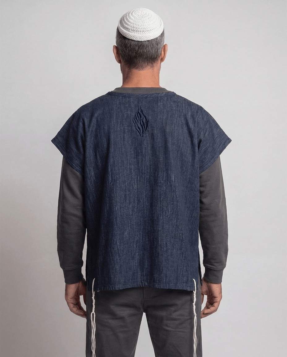 Man wearing tallit katan in denim, back view showing the Aesh Sheli flame embroidery, Kameart