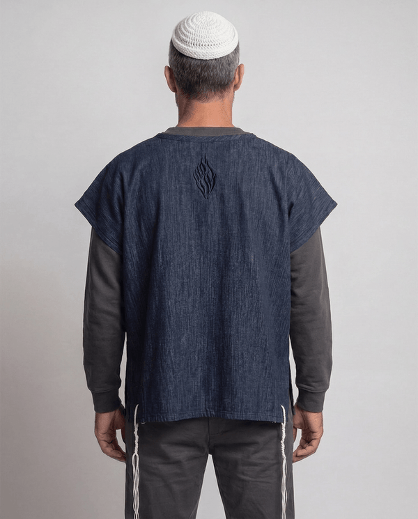 Man wearing tallit katan in denim, back view showing the Aesh Sheli flame embroidery, Kameart